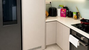 Una cocina moderna con un refrigerador de acero inoxidable, horno empotrado y encimera con diversos utensilios de cocina.