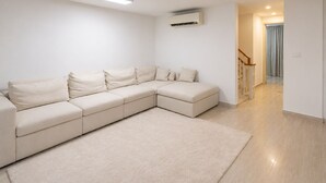 Una sala de estar moderna con un sofá modular, un televisor de pantalla plana y una escalera que sube a otro nivel.