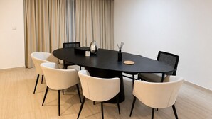 Un comedor moderno con una mesa redonda, seis sillas y un ventanal con cortinas.
