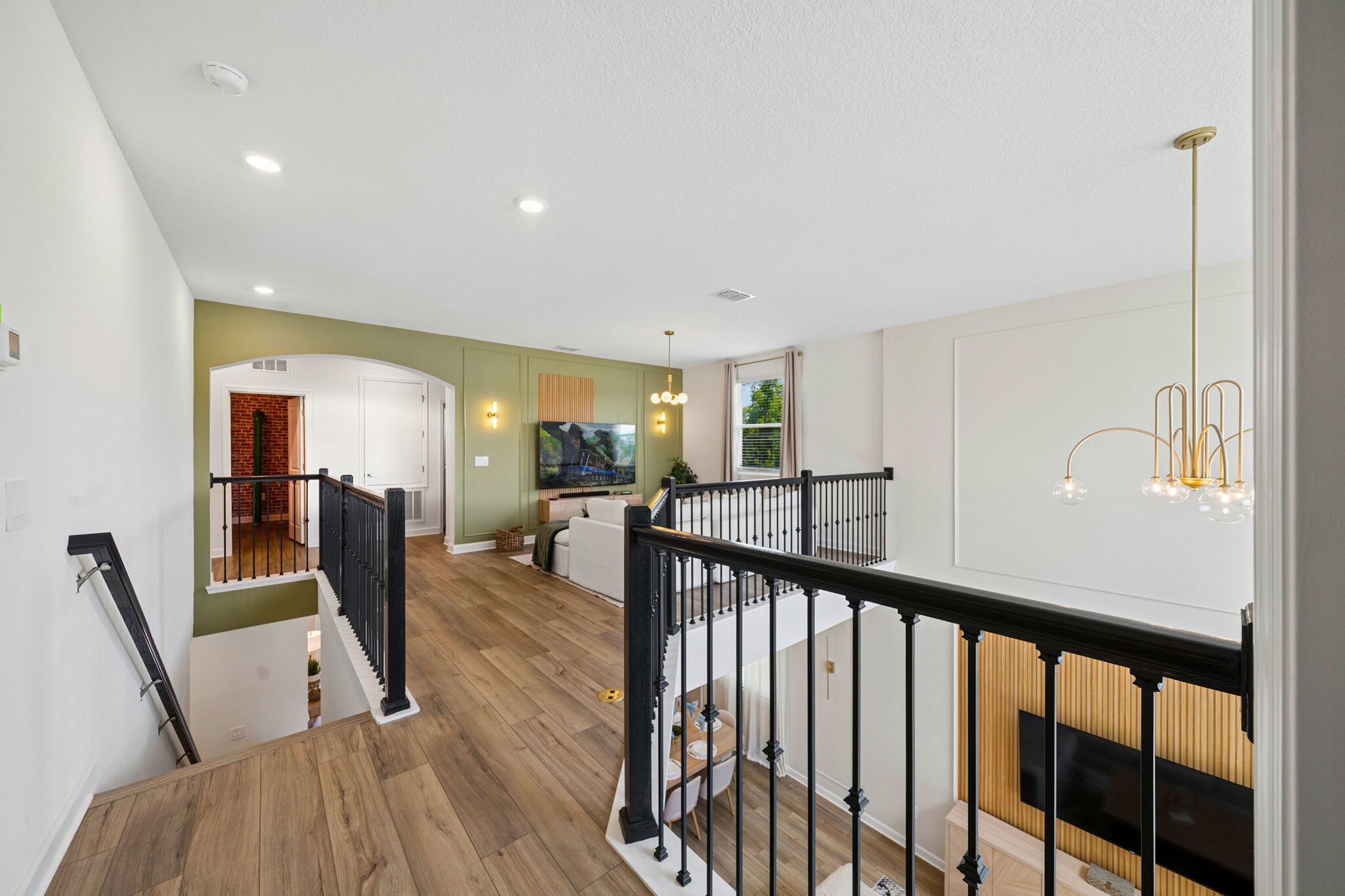 A multi-level interior with a staircase, a dining area, and a living room with a television.
