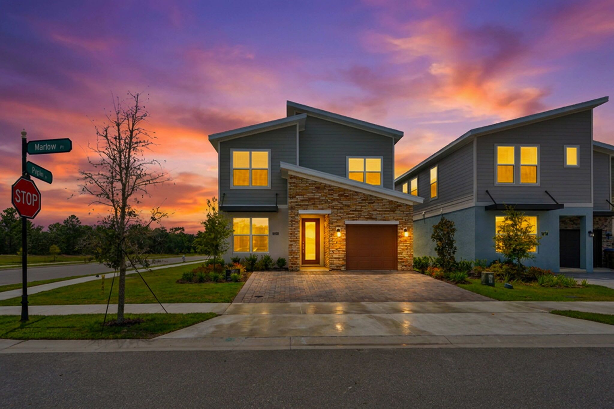 A two-story residential building with a stone facade, a garage, and a driveway leading to the entrance.
