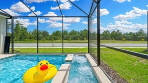 A swimming pool with a duck float, surrounded by a covered area with a view of a road and trees. - Brand New 5BR 5BA Villa w Pool Spa Game Room 7800 (Kissimmee)
