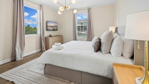A bedroom with a bed, bedside tables, a lamp, and a view of the outdoors. - Brand New 5BR 5BA Villa w Pool Spa Game Room 7800 (Kissimmee)