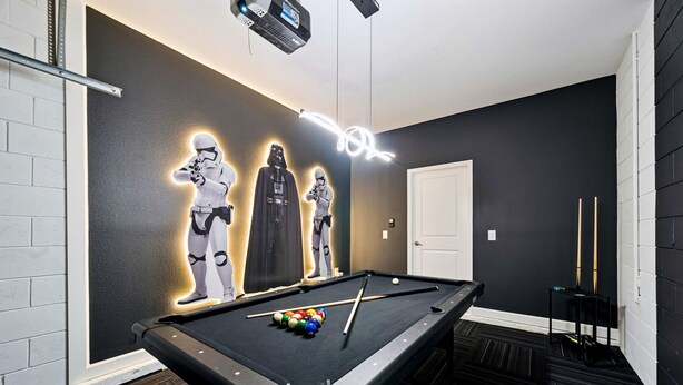 A pool table with balls, a pool cue, and three illuminated Star Wars character figures on the wall. - Brand New 5BR 5BA Villa w Pool Spa Game Room 7800 (Kissimmee)