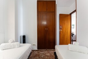 Ein Hotelzimmer mit zwei Betten, einem Holzschrank, einem Spiegel und einem Fenster.