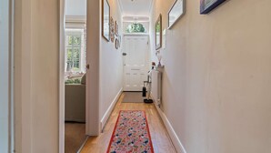 Ein Korridor mit einer weißen Tür, einem Heizkörper und einem Teppich mit Blumenmuster.