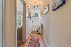 A hallway with a white door, a radiator, and a floral rug. - Charming 2-bed Home Away From Home in Nantwich (Nantwich)