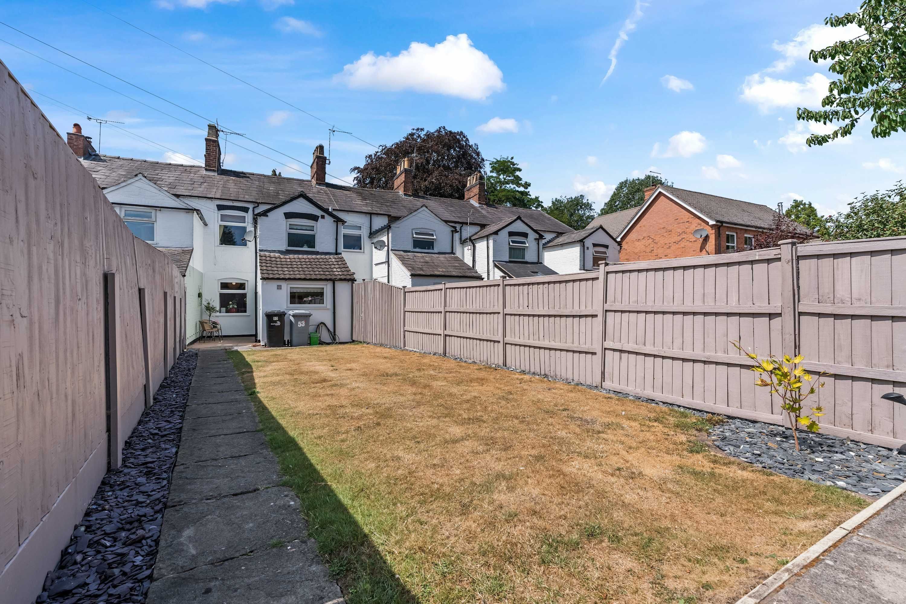 A residential property with a fenced backyard, a paved pathway, and a small garden area.