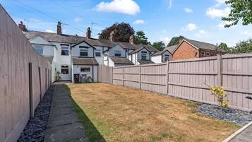 A residential property with a fenced backyard, a paved pathway, and a small garden area.