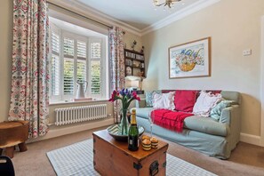 A cozy living room with a sofa, a wooden chest, and a window with curtains. - Charming 2-bed Home Away From Home in Nantwich (Nantwich)