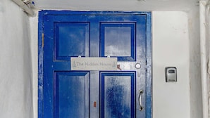 Une porte bleue avec une pancarte sur laquelle on peut lire : « La Maison cachée ».
