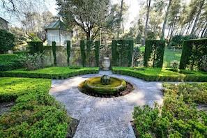 A formal garden with a central fountain, trimmed hedges, and a conservatory. - Mas Les Cigales in Saint-r My-de-provence (St.-Rémy-de-Provence)