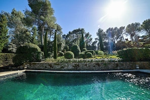 A swimming pool surrounded by manicured gardens and tall trees. - Mas Les Cigales in Saint-r My-de-provence (St.-Rémy-de-Provence)