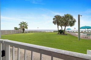 A grassy area with a white fence, palm trees, and a view of the ocean. - Sunswept 102 by Liquid Life (Orange Beach)