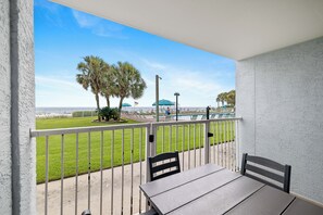 Un balcon avec vue sur une plage, une piscine et un drapeau.