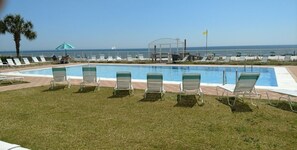 Ein Poolbereich mit Liegestühlen und freiem Blick auf das Meer.