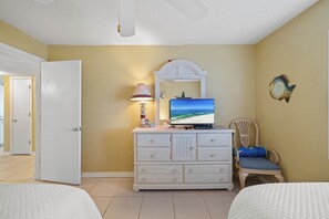 A hotel room with a bed, a dresser, a television, and a chair. - Sunswept 108 by Liquid Life (Orange Beach)