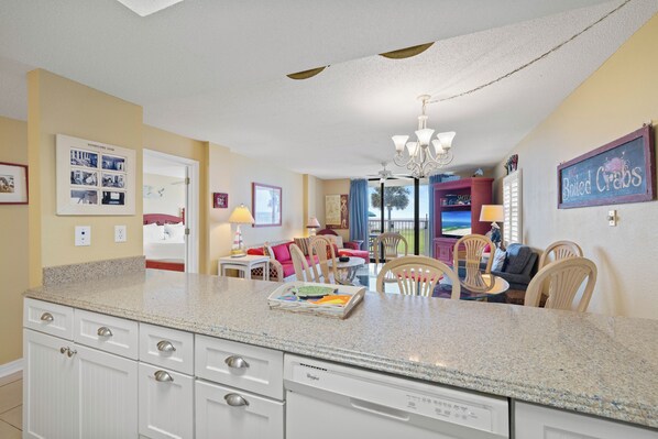 A kitchen with granite countertops, white cabinetry, and a built-in dishwasher. - Sunswept 108 by Liquid Life (Orange Beach)