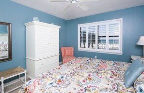 A bedroom with a bed, a dresser, a chair, a window, and a ceiling fan. - Sunswept 203 by Liquid Life (Orange Beach)