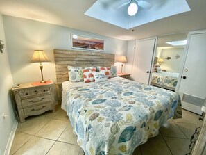 A bedroom with a bed, bedside tables, a ceiling fan, a wall-mounted picture, and a wardrobe. - Sunswept 204 by Liquid Life (Orange Beach)