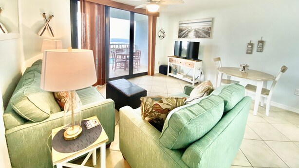 A living room with a sofa, a table, a lamp, a TV, and a balcony with a view. - Sunswept 204 by Liquid Life (Orange Beach)