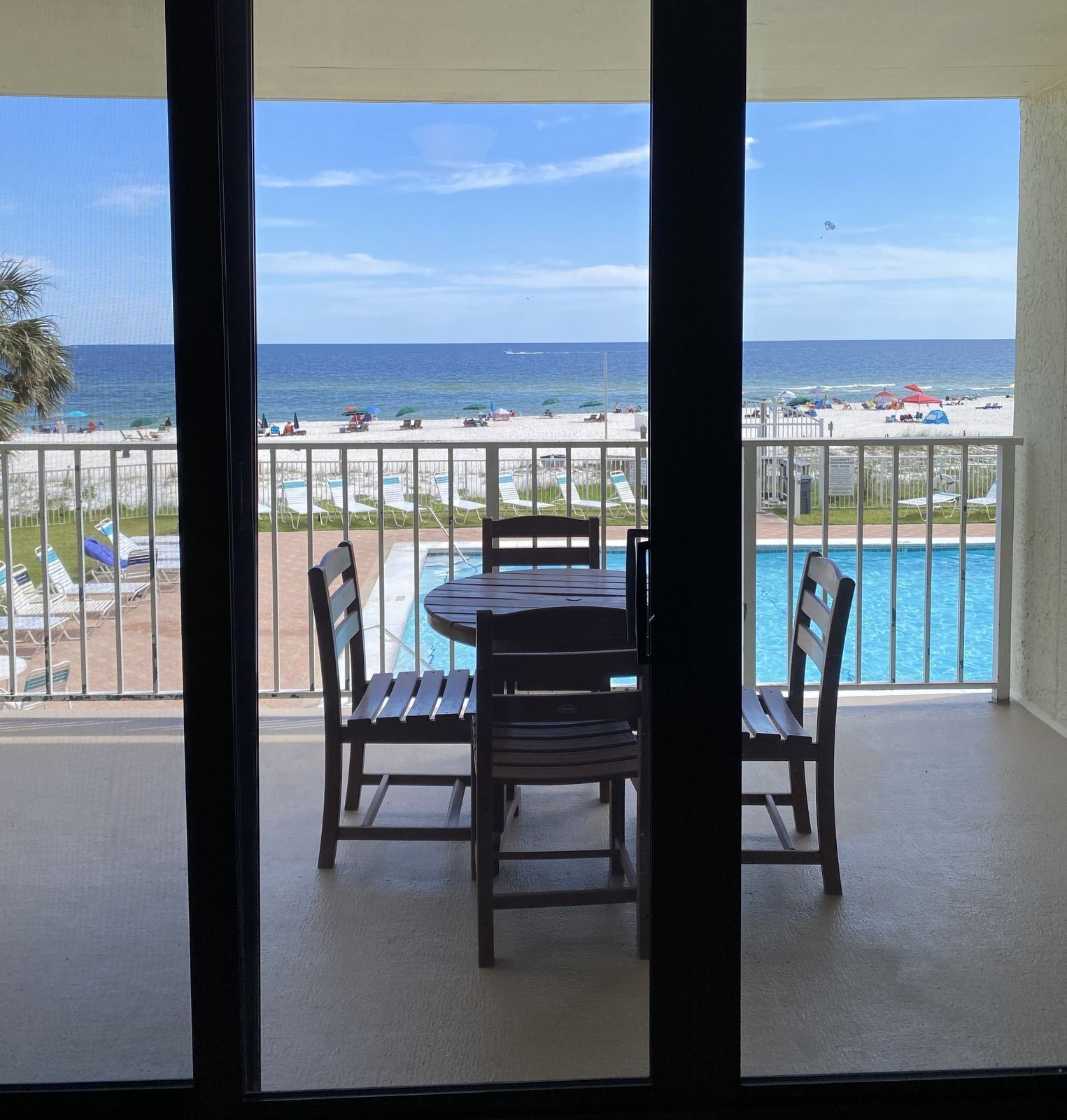 A balcony with a pool and a view of the beach.