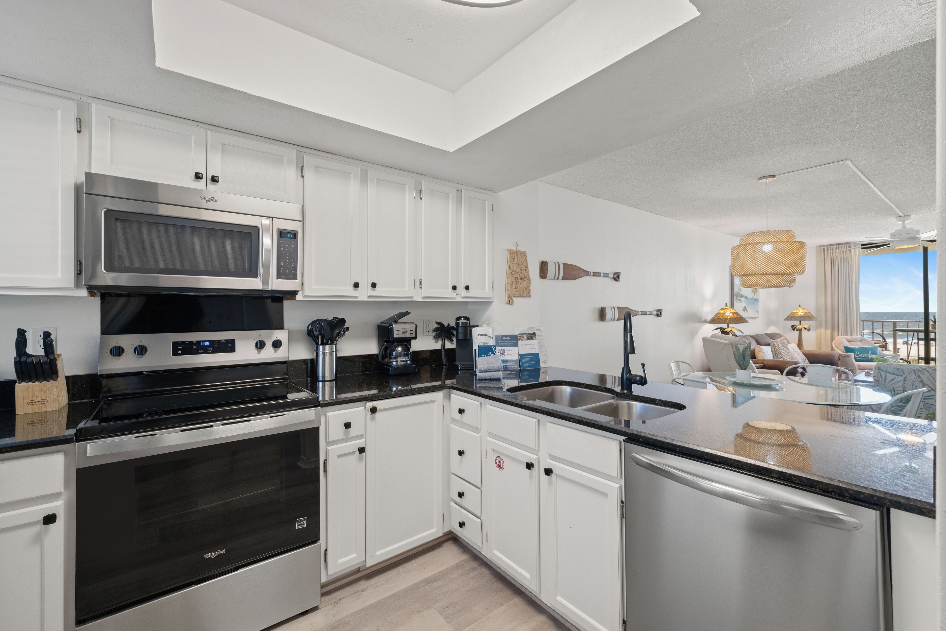 A modern kitchen with white cabinetry, stainless steel appliances, and a view to the outside.