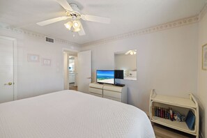 Ein Hotelzimmer mit Bett, Fernseher, Bücherregal und Deckenventilator.