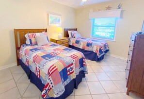 Ein Schlafzimmer mit zwei Betten, jedes mit einer gesteppten Tagesdecke im patriotischen Design.