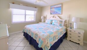 A bedroom with a bed, nightstands, a dresser, a window with blinds, and a painting on the wall. - Sunswept 301 by Liquid Life (Orange Beach)