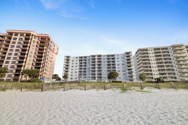 A beachfront hotel with multiple floors, balconies, and a sandy beach in the foreground. - Sunswept 304 by Liquid Life (Orange Beach)