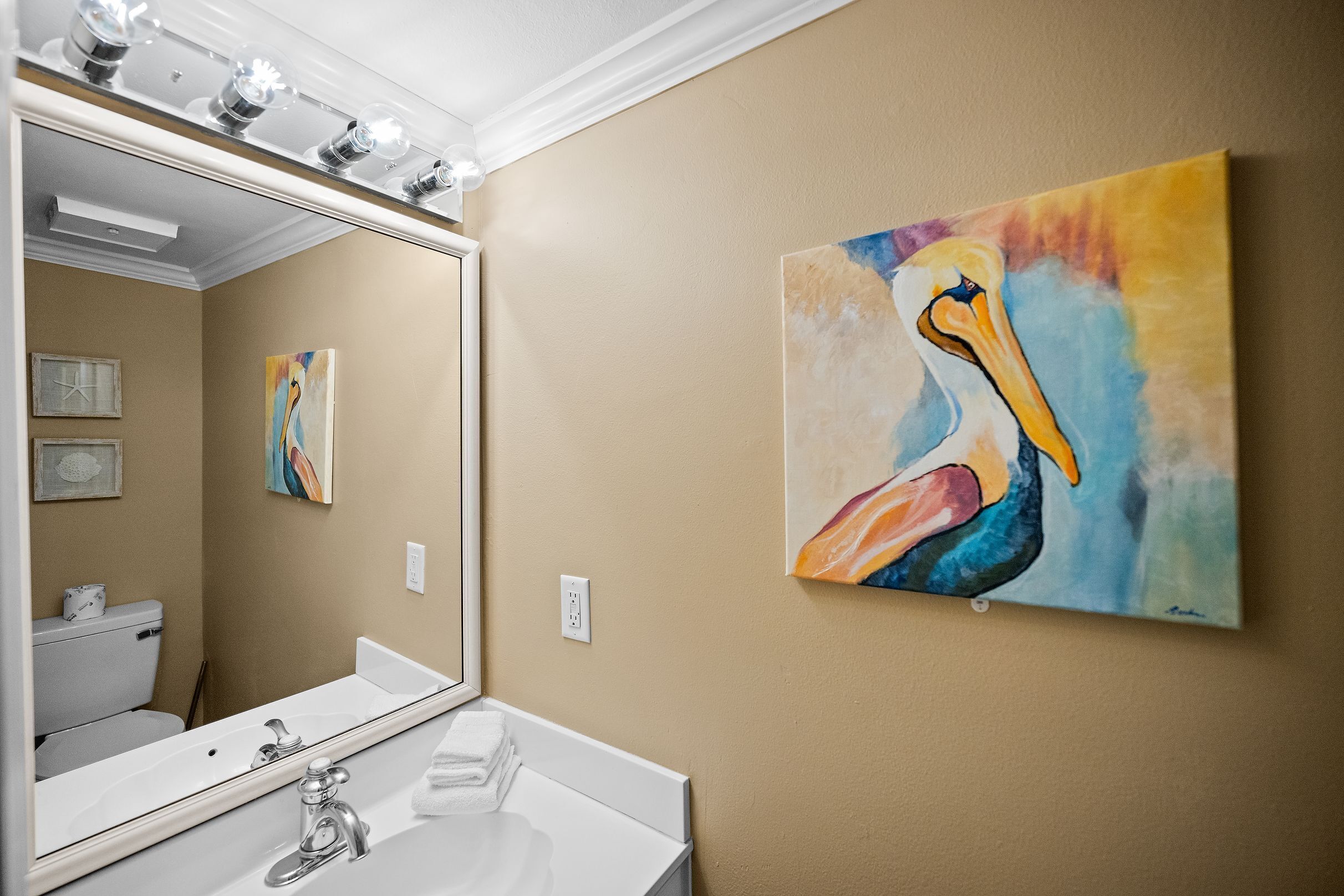 Ein Badezimmer mit einem weißen Waschbecken, einem Spiegel und einem Vogelbild an der Wand.