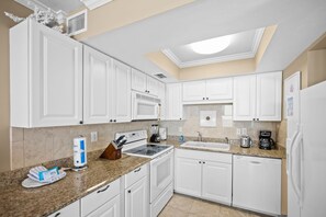 A modern kitchen with white cabinetry, a granite countertop, and a skylight. - Sunswept 304 by Liquid Life (Orange Beach)