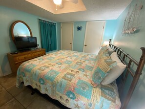 A bedroom with a bed, a dresser, a television, and a door. - Sunswept 305 by Liquid Life (Orange Beach)