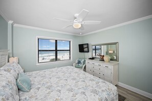 A bedroom with a bed, a dresser, a ceiling fan, a window with a beach view, and a television. - Sunswept 402 by Liquid Life (Orange Beach)