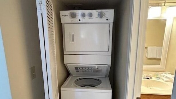 A laundry room with stacked appliances, a door leading to a bathroom, and a tiled floor. - Sunswept 403 by Liquid Life (Orange Beach)