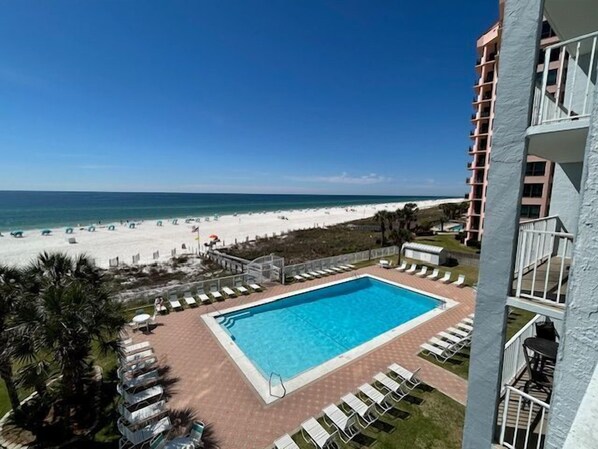 A swimming pool with a view of the beach and ocean, surrounded by lounge chairs and a fence. - Sunswept 403 by Liquid Life (Orange Beach)