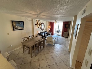 A dining area with a table and chairs, a sofa, and a television in the background. - Sunswept 403 by Liquid Life (Orange Beach)