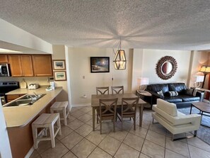A compact living space with a kitchenette, dining area, and seating area. - Sunswept 403 by Liquid Life (Orange Beach)