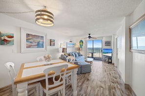 A spacious living area with a dining table, seating, and a view of the ocean. - Sunswept 407 by Liquid Life (Orange Beach)