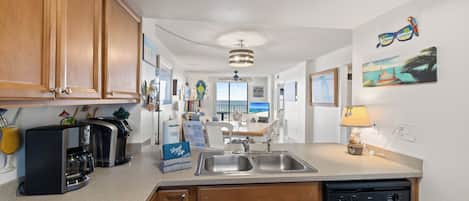 A modern kitchen with wooden cabinets, a coffee maker, and a dishwasher.