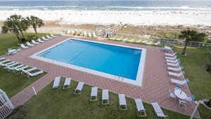 Une piscine avec des chaises longues et vue sur la plage.