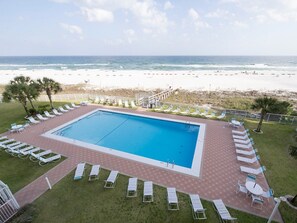Ein Swimmingpool mit Liegestühlen und Blick auf den Strand.