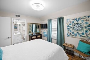 A bedroom with a bed, dresser, mirror, and artwork on the wall. - Sunswept 408 by Liquid Life (Orange Beach)