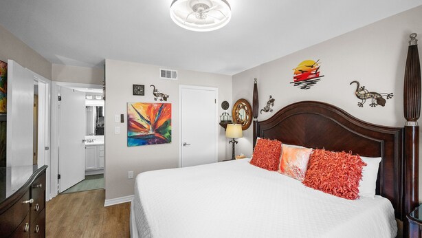 Quarto de hotel com uma cama grande, ventoinha no teto e obras de arte nas paredes.