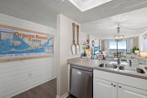 Una cocina con un lavamanos de acero inoxidable, lavavajillas y un mapa de Orange Beach, Alabama en la pared.