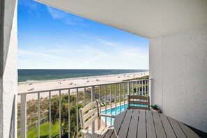 Un balcón con vista a una playa y una piscina.