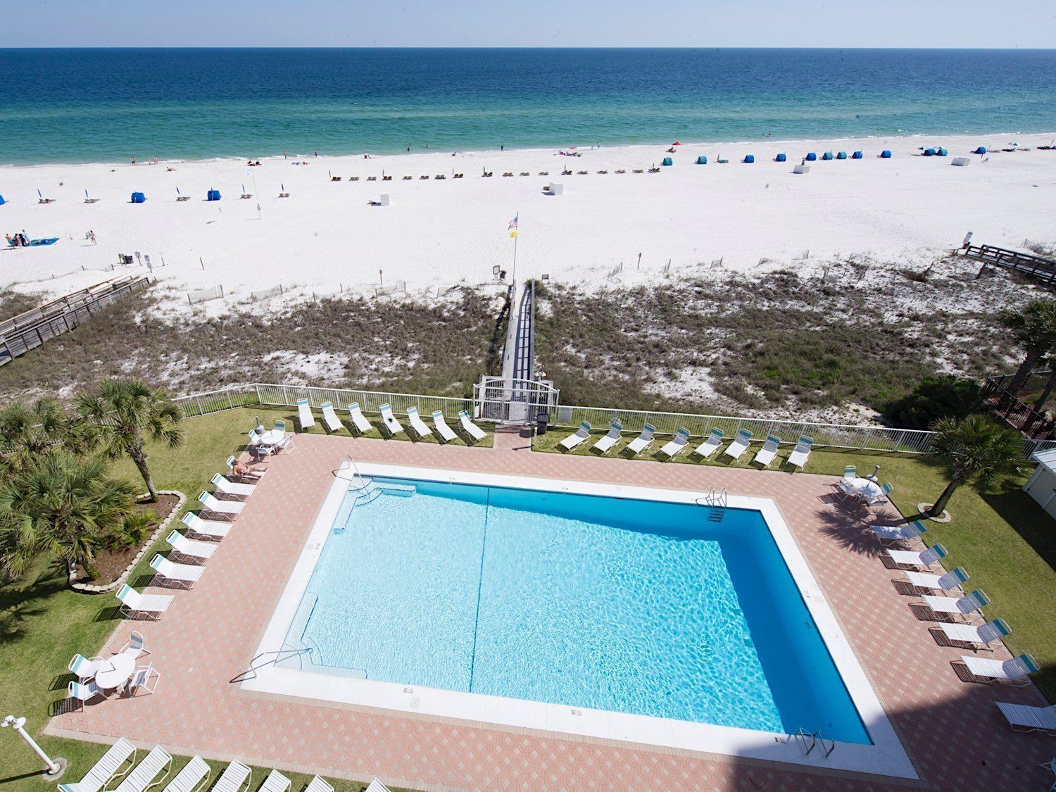 Ein Swimmingpool mit Liegestühlen und Blick auf den Strand.
