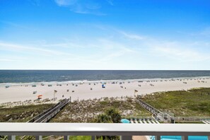 A beach with a clear sky, a sandy shore, and a pool area with lounge chairs. - Sunswept 602 by Liquid Life (Orange Beach)