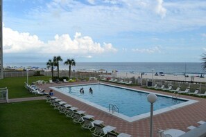 Ein Pool mit Liegestühlen und Blick auf den Strand.
